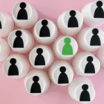 Copos brancos com ícones de figuras pretas e uma figura verde em destaque sobre fundo rosa