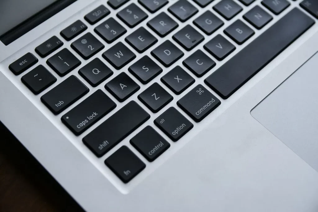 Close-up de teclado de laptop com teclas pretas, incluindo shift, caps lock, control, alt, option e command.