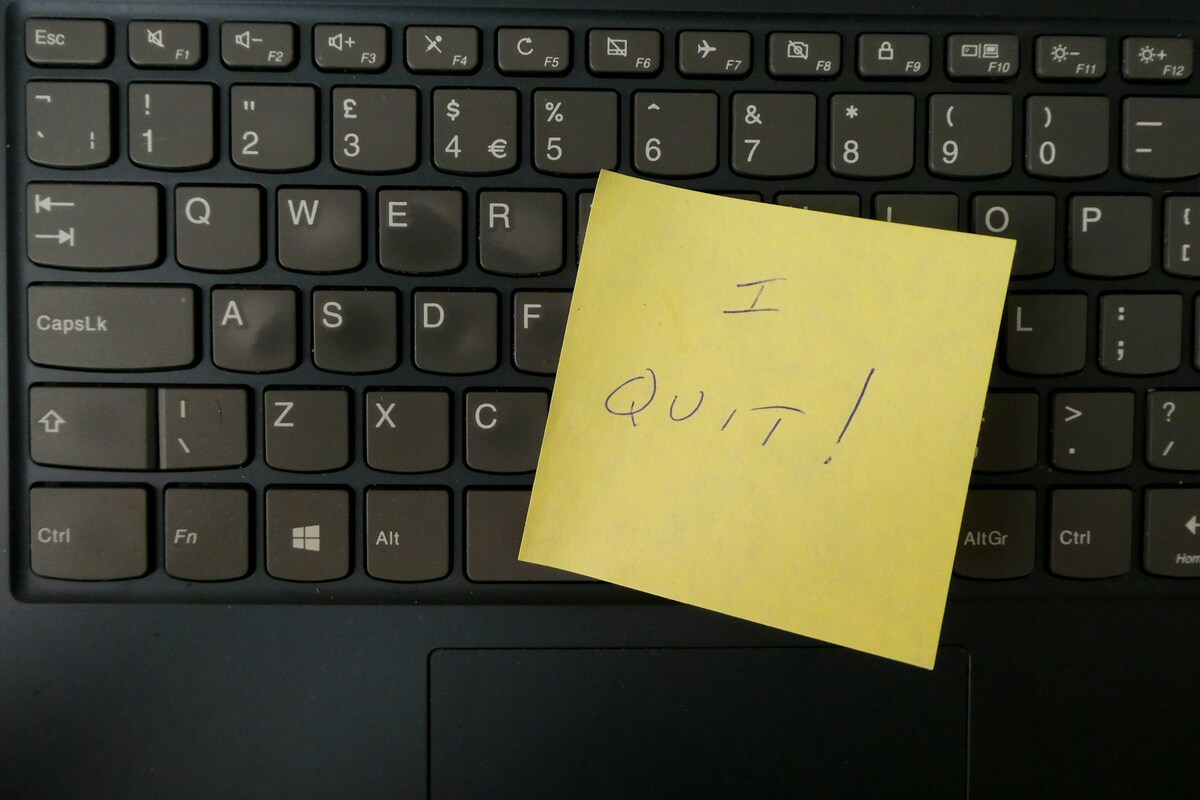 Bilhete amarelo com a frase 'I QUIT!' em cima de um teclado de notebook.