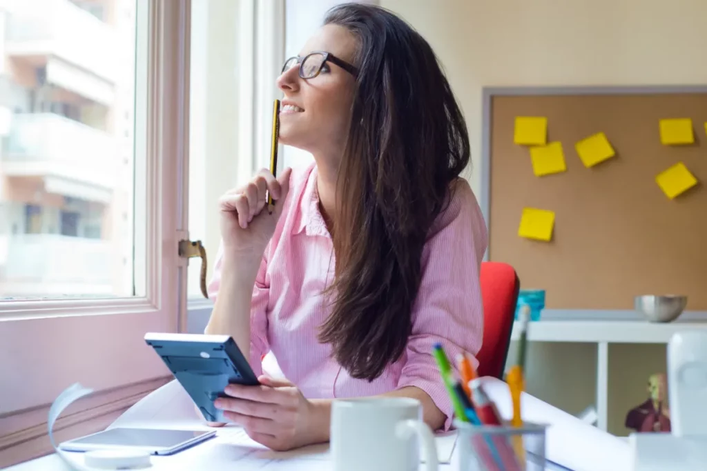 Mulher com celular na mão, olhando para frente e sorrindo