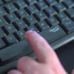 Dedo pressionando a tecla Silent Touch em teclado silencioso para digitação confortável
