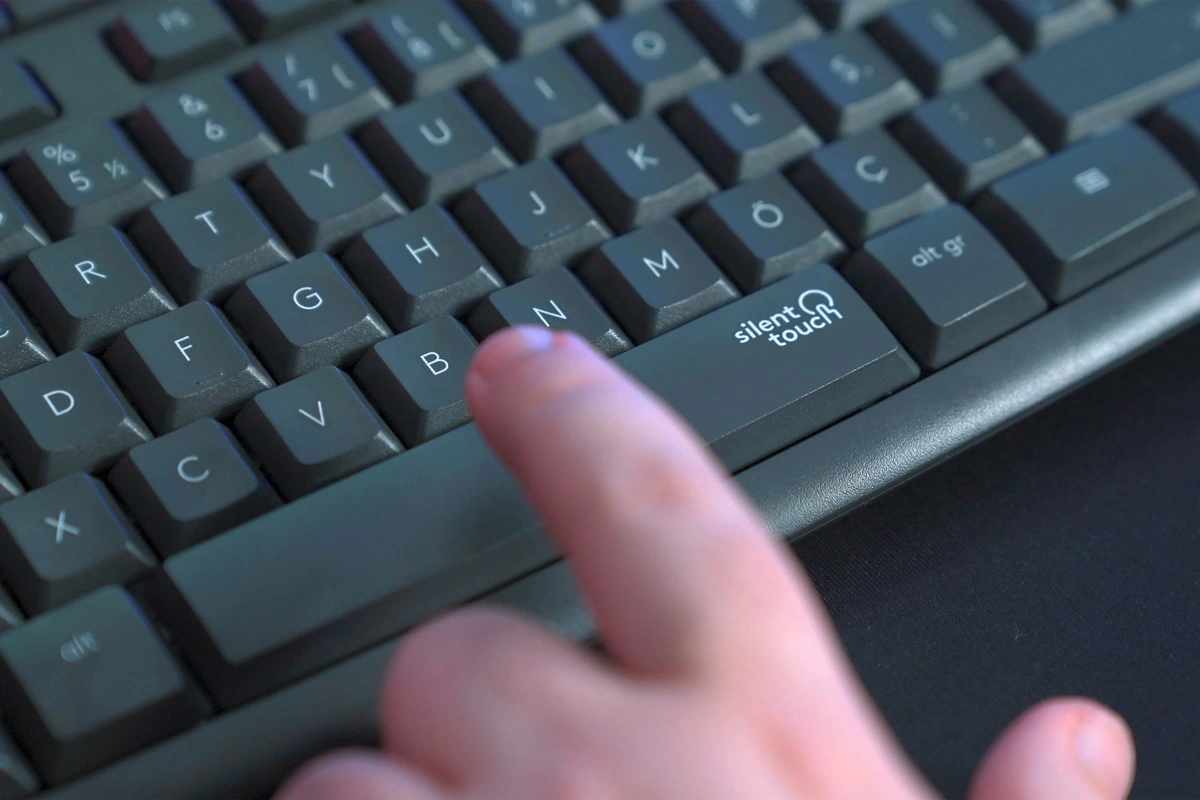 Dedo pressionando a tecla Silent Touch em teclado silencioso para digitação confortável