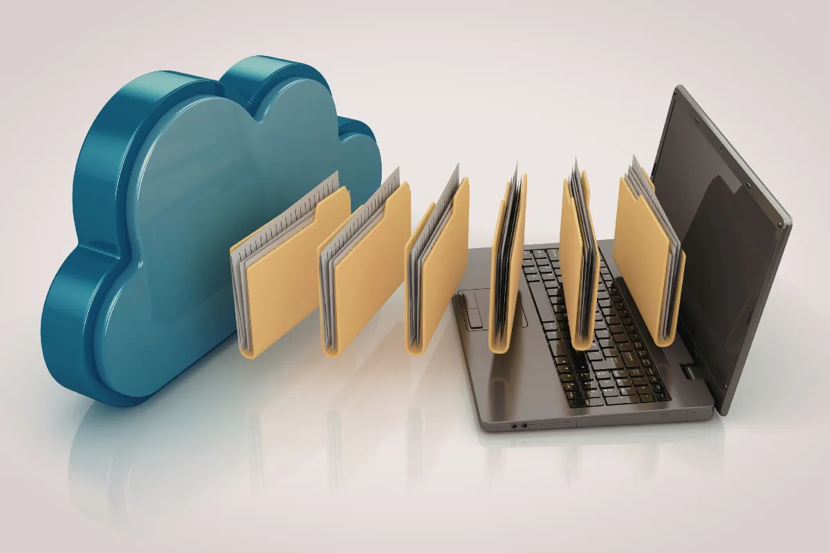 Imagem de um laptop com arquivos em cima e, do lado, uma nuvem