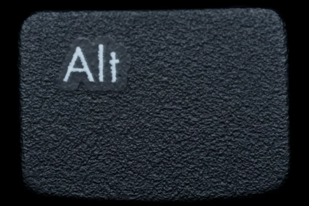 tecla Alt preta em close com textura detalhada e iluminação destacando a inscrição