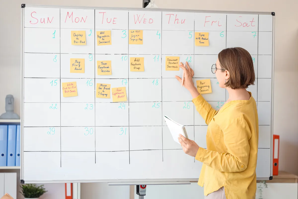 Mulher usando quadro branco e post-its para planejar a semana.
